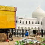 Желтый кузов грузового автомобиля и бетономешалка на фоне белоснежных зданий Белой Мечети